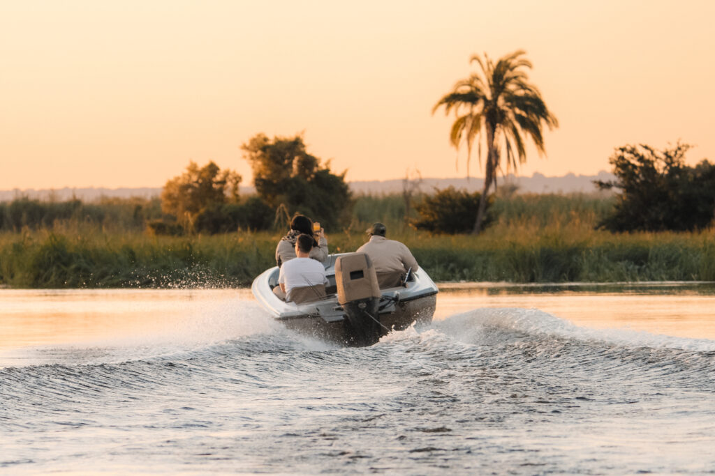 A boat running upriver at sunset with three anglers aboard